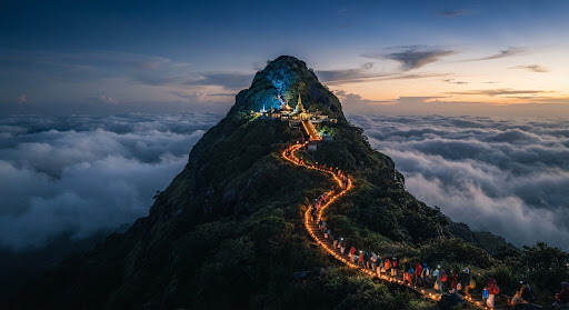 Weitläufige Teeterrassen ziehen sich in sanften, smaragdgrünen Tälern hinab, dahinter nebelverhangene Berge bei Nuwara Eliya, Sri Lanka, im stillen Morgendunst.