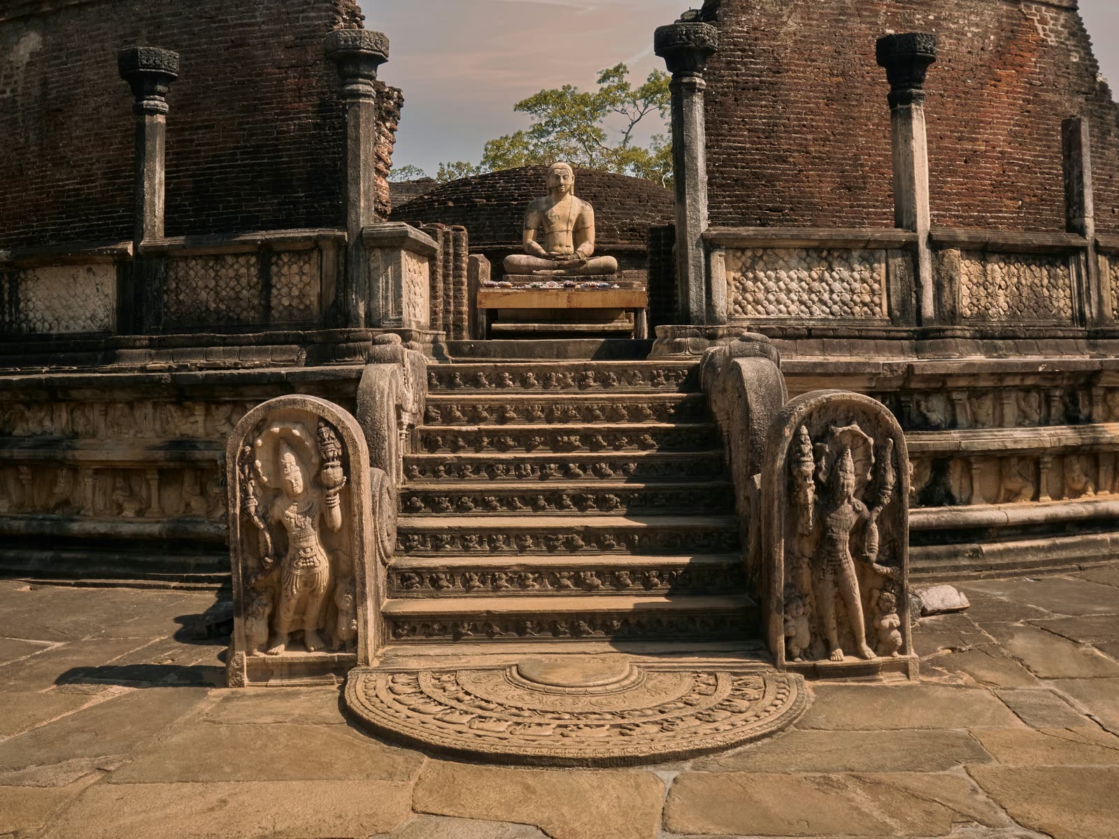 The ancient Vatadage of Polonnaruwa, with a seated Buddha above carved guard stones and a moonstone at the foot of the stairs