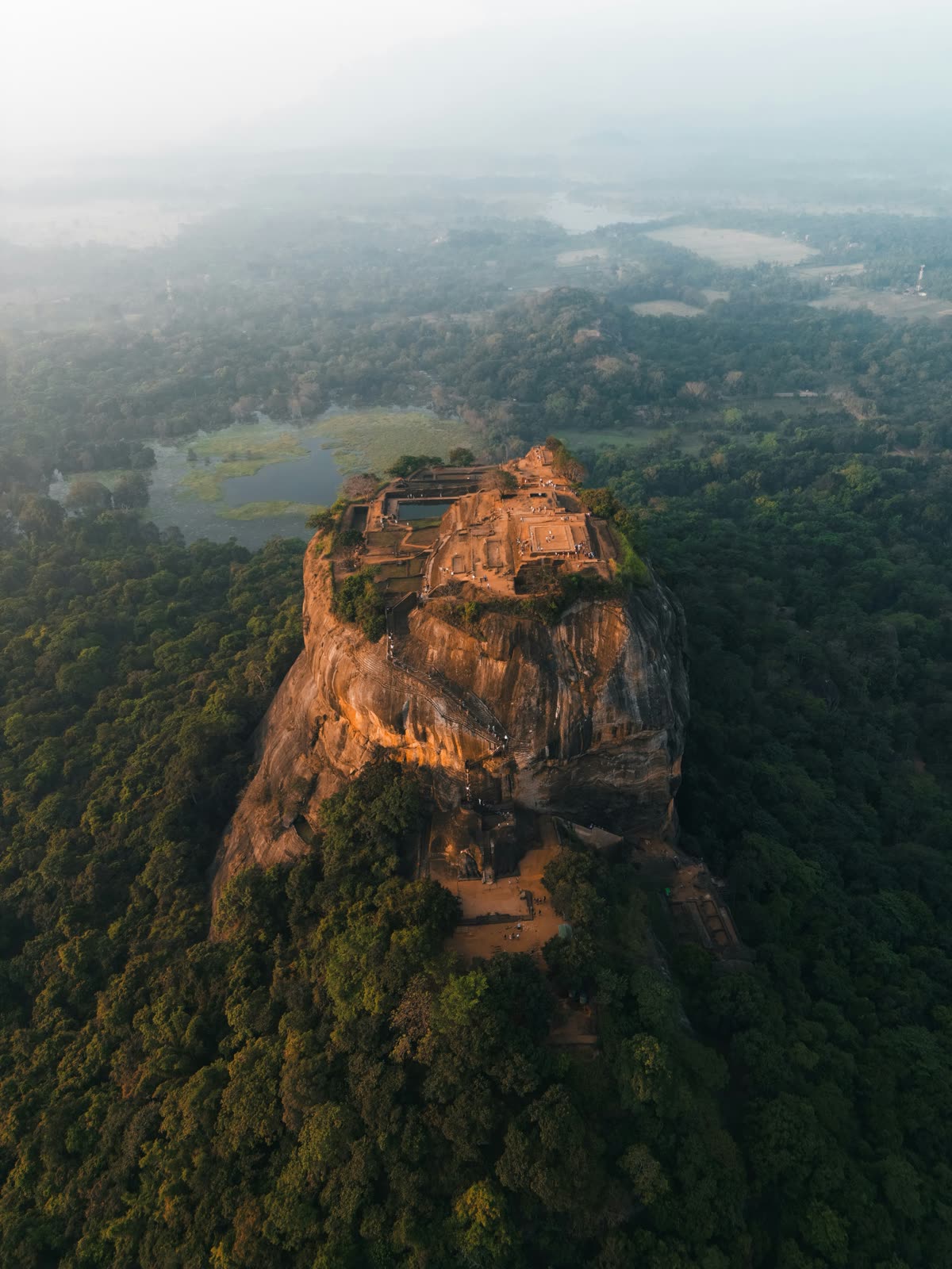 Aerial view of Sigiriya Rock Fortress rising above the jungle in the morning haze